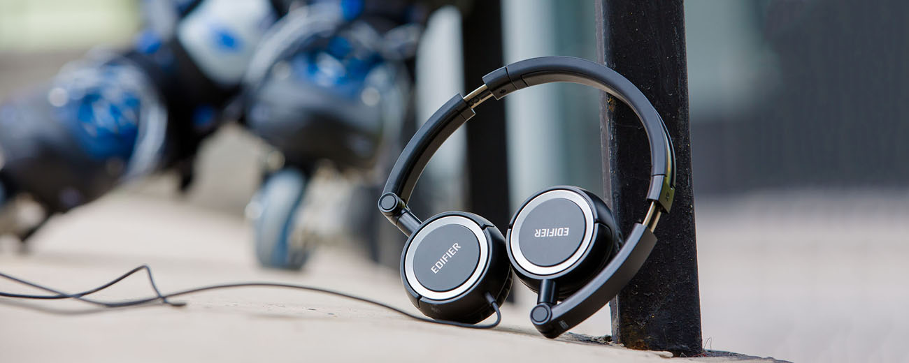 Folded black H650 On-Ear Headphones are leaning against a post.